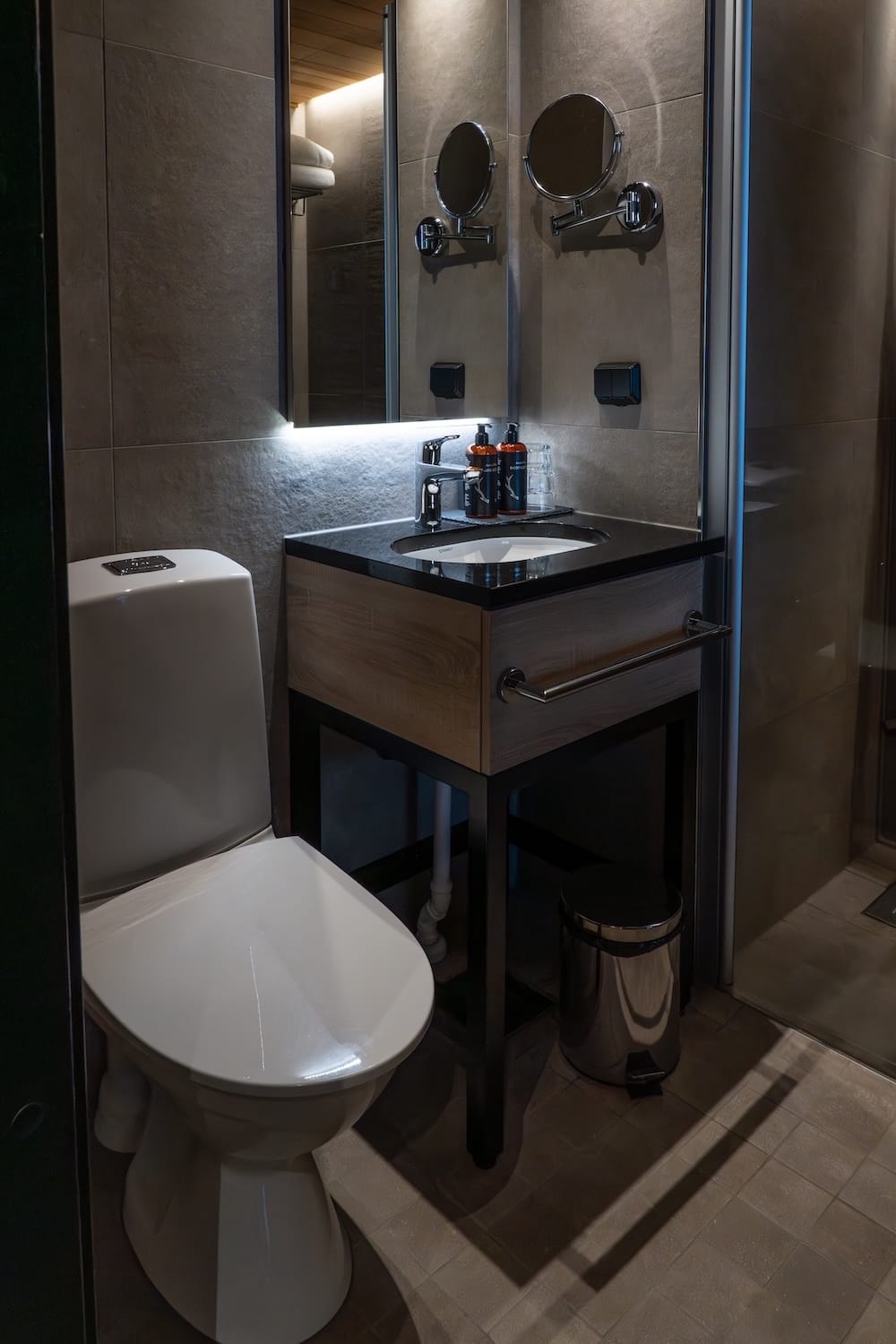 A bathroom in my hotel room - a toilet and shower and a sink with two branded soap/lotions on it