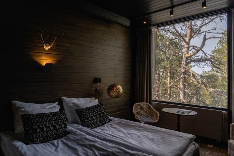 Lapland Hotels Sky Ounasvaara review - this is the view from my room with a lot of trees outside. There is a bed and pillows, as well as a chair and table in the background